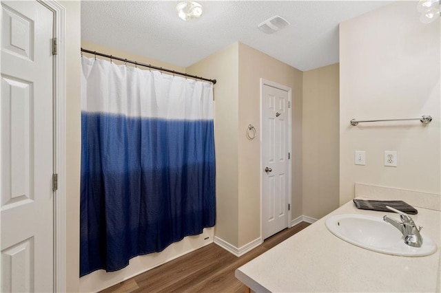 bathroom with vanity, hardwood / wood-style flooring, a textured ceiling, and curtained shower