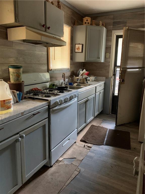 kitchen featuring a wealth of natural light, white gas stove, and wood walls