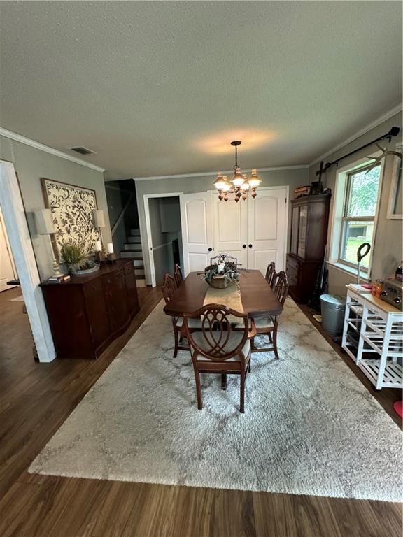 dining area with crown molding, dark wood-type flooring, and a chandelier