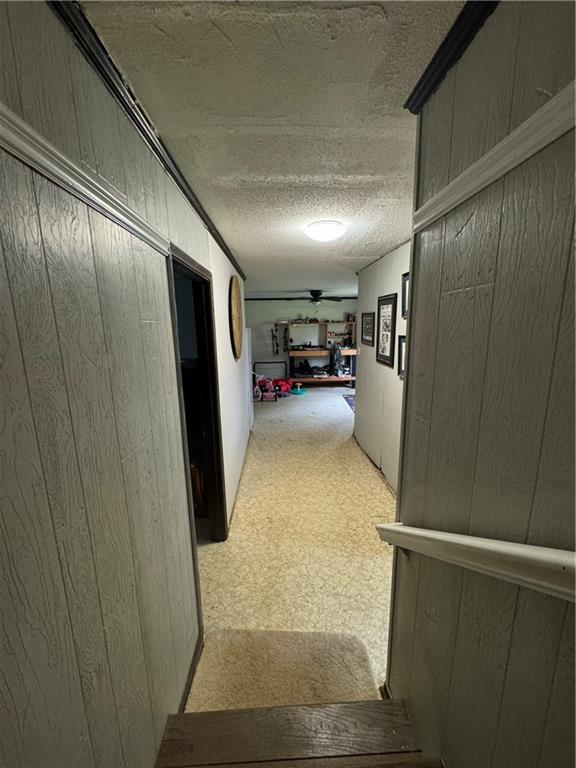 hall with wooden walls and a textured ceiling