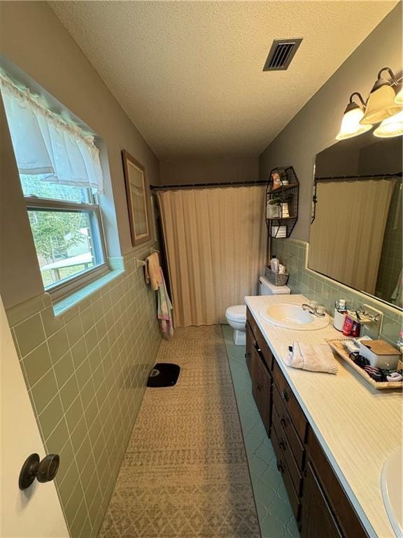 bathroom featuring vanity, tile walls, a textured ceiling, and toilet