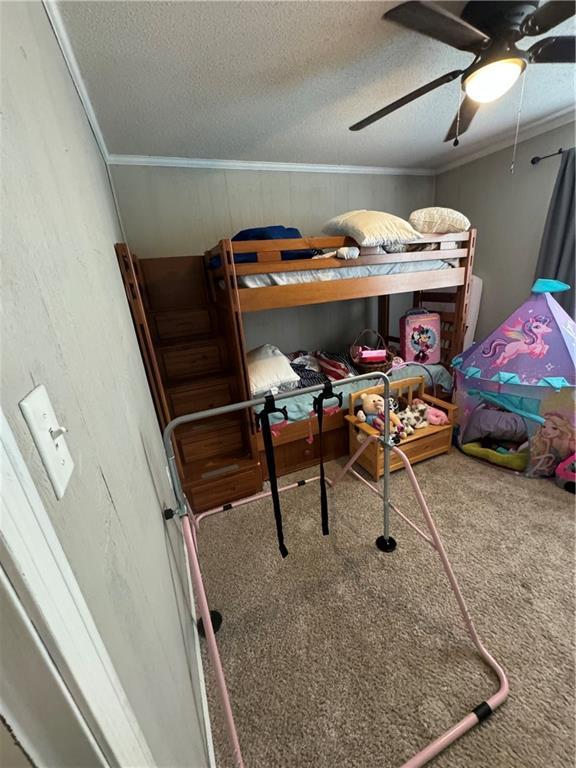 bedroom with crown molding, ceiling fan, carpet flooring, and a textured ceiling