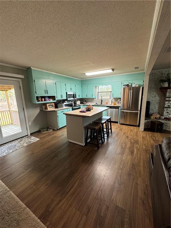 kitchen featuring stainless steel appliances, a center island, a kitchen breakfast bar, and dark hardwood / wood-style floors