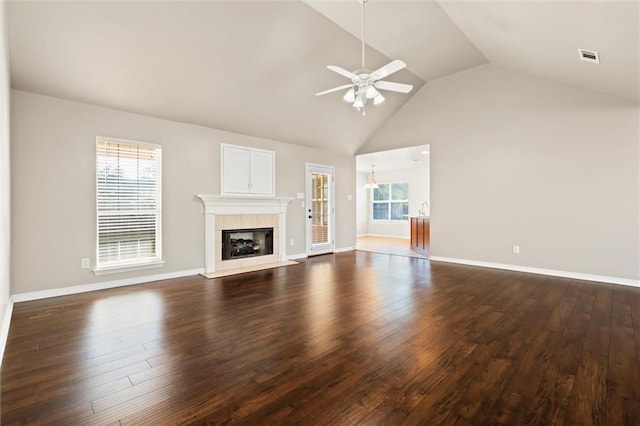 unfurnished living room featuring ceiling fan, lofted ceiling, dark wood-type flooring, and a tiled fireplace