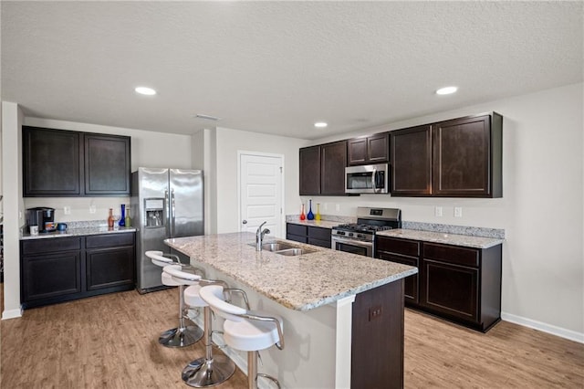 8320 Ogilvy Ct, Daphne, AL 36526 - kitchen with an island with sink, a breakfast bar area, a sink, light wood finished floors, and stainless steel appliances