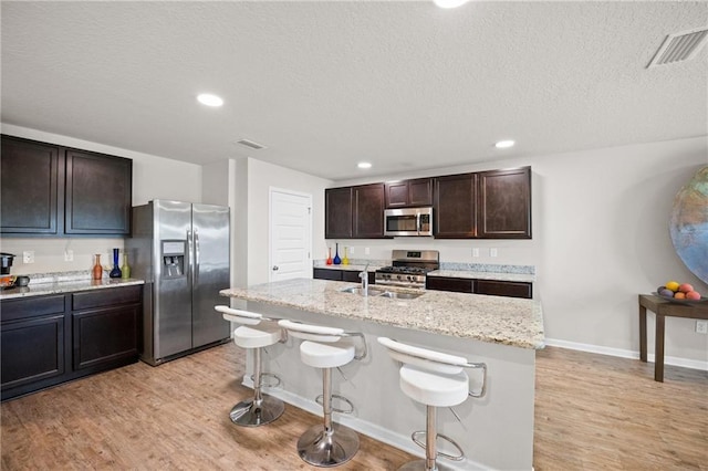 8320 Ogilvy Ct, Daphne, AL 36526 - kitchen featuring visible vents, a breakfast bar area, a sink, light wood finished floors, and stainless steel appliances