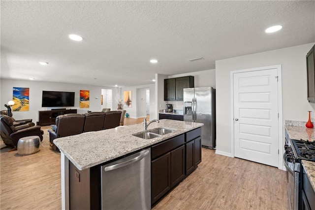 8320 Ogilvy Ct, Daphne, AL 36526 - kitchen featuring a textured ceiling, light wood-type flooring, a sink, stainless steel appliances, and an island with sink