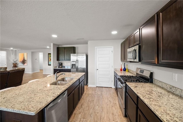 8320 Ogilvy Ct, Daphne, AL 36526 - kitchen featuring stainless steel appliances, dark brown cabinetry, a sink, and light wood-style flooring