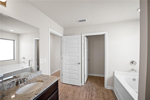 8320 Ogilvy Ct, Daphne, AL 36526 - bathroom featuring a textured ceiling, a bath, visible vents, wood finished floors, and vanity