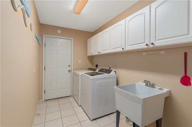 clothes washing area featuring washer and dryer, sink, light tile patterned floors, and cabinets