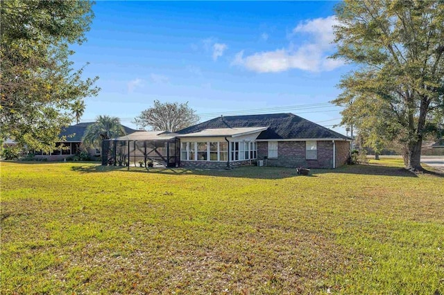 rear view of house with a lawn, glass enclosure, and a sunroom