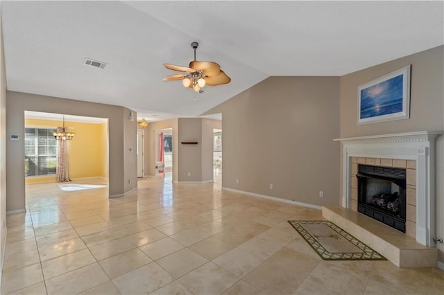 unfurnished living room with light tile patterned flooring, ceiling fan with notable chandelier, vaulted ceiling, and a tiled fireplace