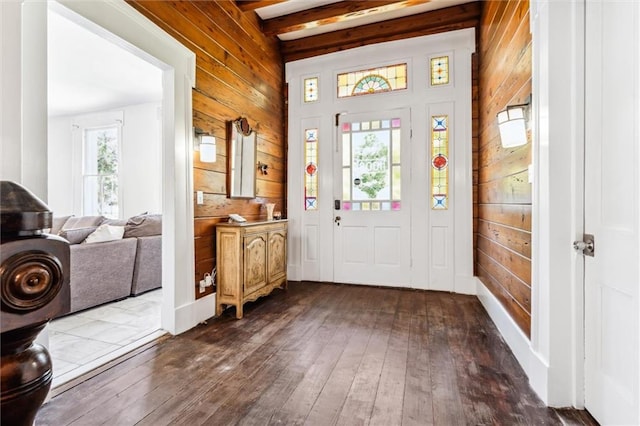 entryway with beamed ceiling, dark hardwood / wood-style floors, and wood walls