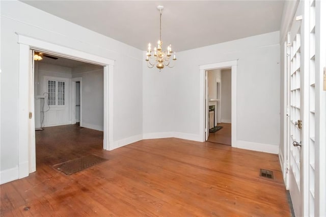 spare room featuring hardwood / wood-style flooring and ceiling fan with notable chandelier