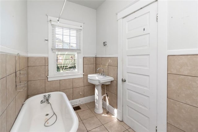 bathroom featuring a tub to relax in, tile patterned floors, and tile walls