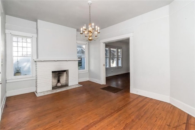 unfurnished living room with hardwood / wood-style flooring, an inviting chandelier, and a fireplace