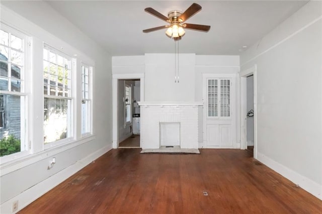 unfurnished living room featuring a brick fireplace, ceiling fan, and dark hardwood / wood-style flooring