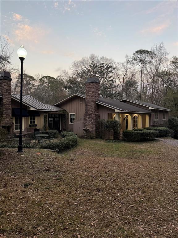 rear view of property with board and batten siding, a chimney, and metal roof