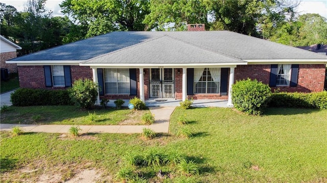 single story home featuring brick siding, a chimney, and a front yard