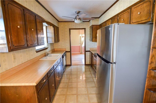 kitchen with wallpapered walls, appliances with stainless steel finishes, ornamental molding, and a sink