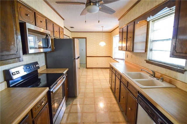 kitchen with wallpapered walls, ornamental molding, light floors, and stainless steel appliances
