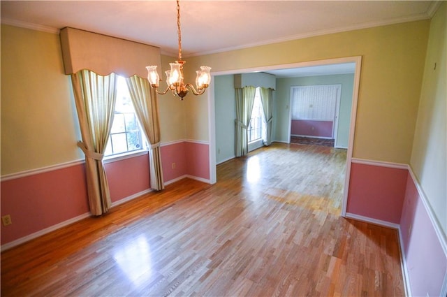 unfurnished room featuring baseboards, a notable chandelier, ornamental molding, and wood finished floors