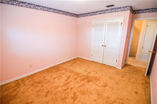 unfurnished bedroom featuring visible vents, baseboards, a closet, and light carpet
