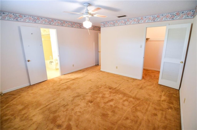 unfurnished bedroom featuring carpet flooring, visible vents, a spacious closet, and ensuite bath