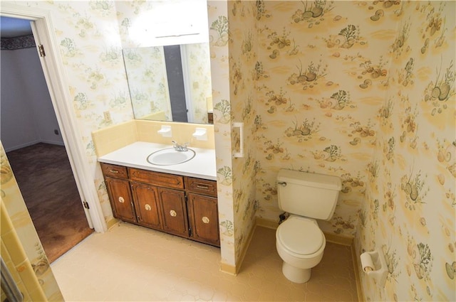 half bathroom featuring vanity, baseboards, toilet, and wallpapered walls