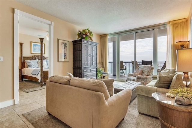 living room with light tile patterned floors, a textured ceiling, a wall of windows, and baseboards