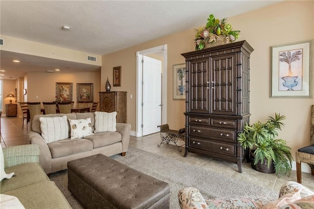 living room featuring light tile patterned floors, visible vents, a textured ceiling, and recessed lighting