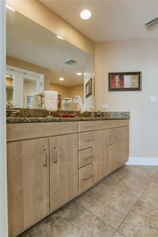 bathroom with tile patterned flooring, visible vents, baseboards, and double vanity