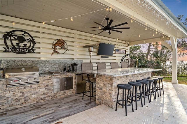 view of patio featuring exterior kitchen, ceiling fan, grilling area, and exterior bar