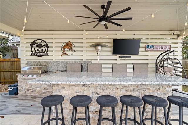 interior space with light stone counters, a kitchen bar, and ceiling fan