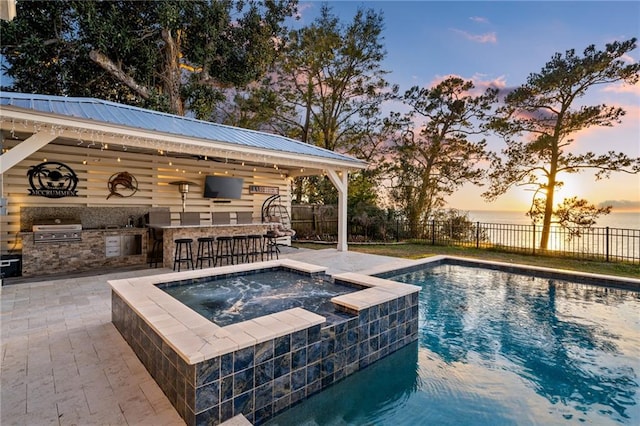 view of swimming pool featuring a grill, an in ground hot tub, a patio, an outdoor bar, and area for grilling