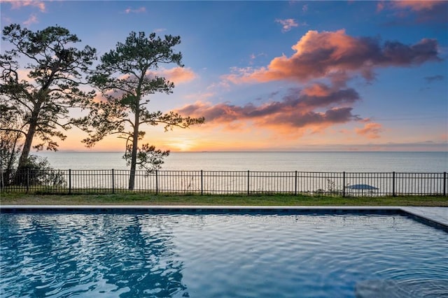 pool at dusk featuring a water view