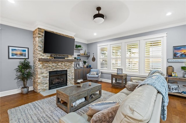 living room featuring dark wood-type flooring, ornamental molding, and a stone fireplace