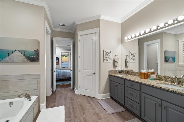 bathroom featuring vanity, hardwood / wood-style flooring, ornamental molding, and a relaxing tiled tub