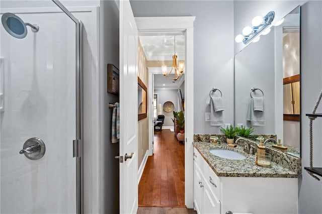 bathroom featuring a shower, hardwood / wood-style floors, ornamental molding, and vanity