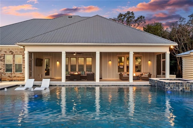 pool at dusk featuring outdoor lounge area, ceiling fan, an in ground hot tub, and a patio