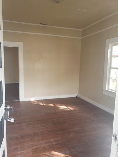 spare room featuring crown molding, a fireplace, baseboards, and wood finished floors