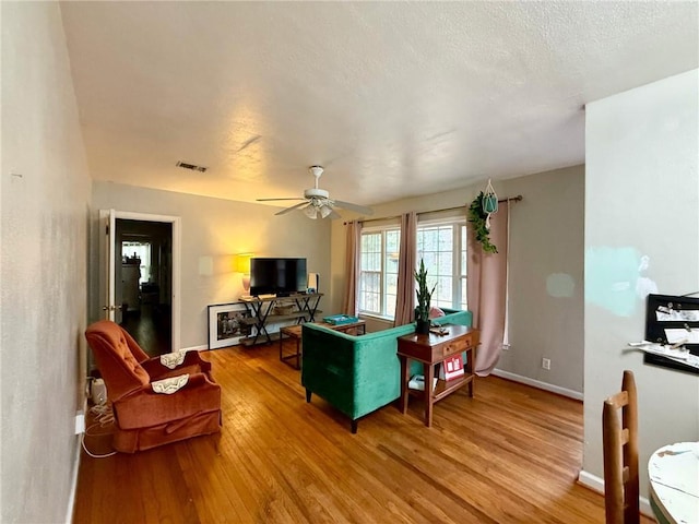 living room featuring ceiling fan, hardwood / wood-style floors, and a textured ceiling