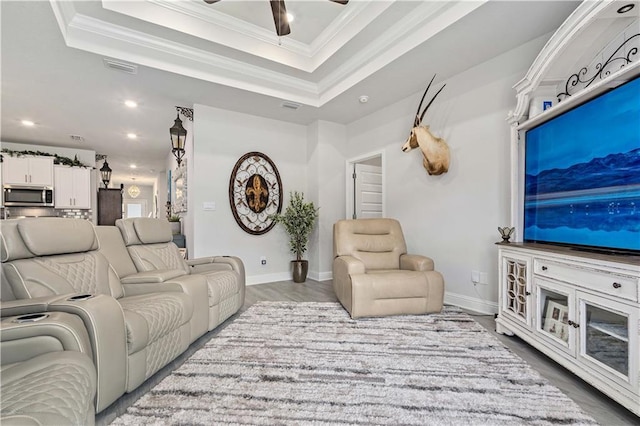 living room featuring crown molding, a tray ceiling, wood-type flooring, and ceiling fan