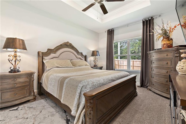 carpeted bedroom with a tray ceiling and ceiling fan