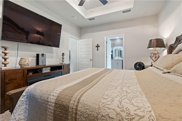 bedroom featuring a raised ceiling, crown molding, ceiling fan, and ensuite bath