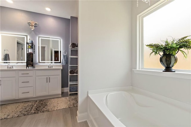 bathroom with hardwood / wood-style flooring, a tub to relax in, and vanity