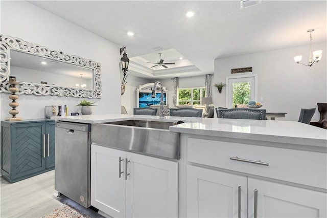 kitchen featuring sink, white cabinetry, a tray ceiling, ceiling fan with notable chandelier, and stainless steel dishwasher