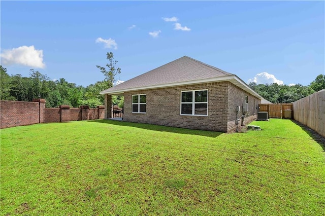 back of property featuring central AC unit and a lawn