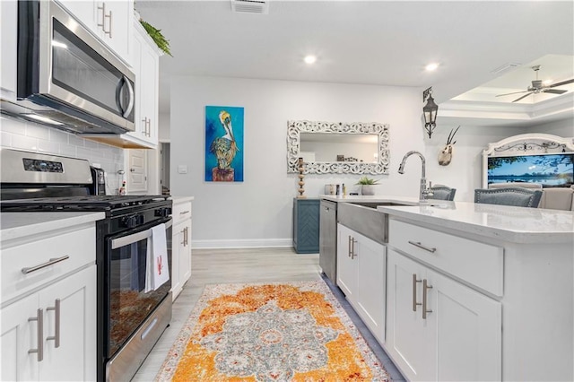 kitchen with white cabinetry, tasteful backsplash, stainless steel appliances, and an island with sink