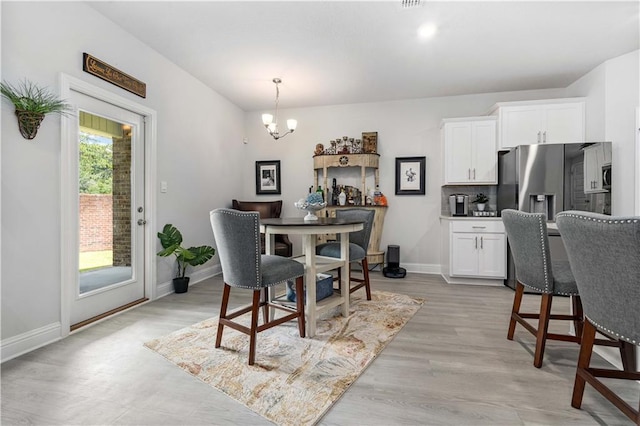 dining area with light hardwood / wood-style flooring and a notable chandelier